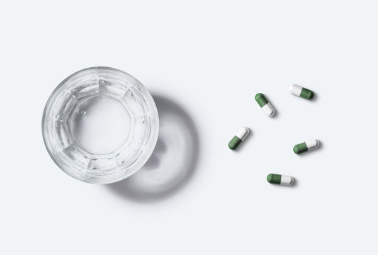 Un verre d'eau et 5 gélules vertes et blanches de Kijimea Côlon Irritable PRO